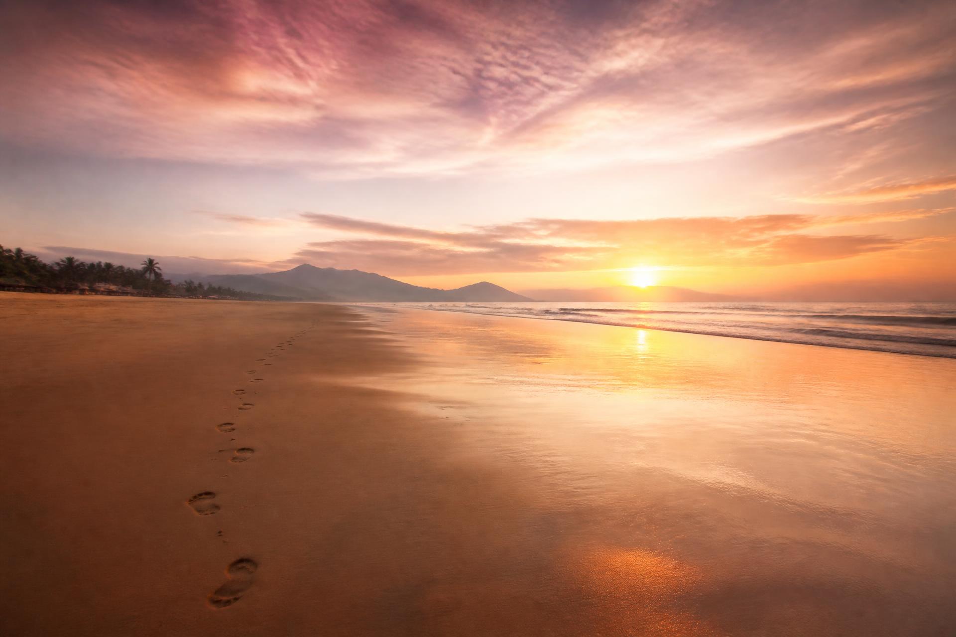 Footprints along an empty beach at sunset in Vietnam
